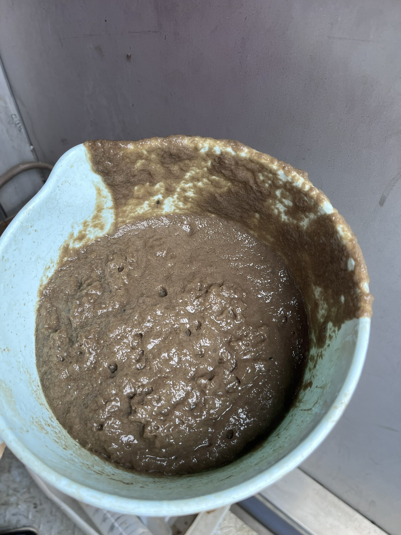 Sticky brown MBR foam sample collected in a field beaker